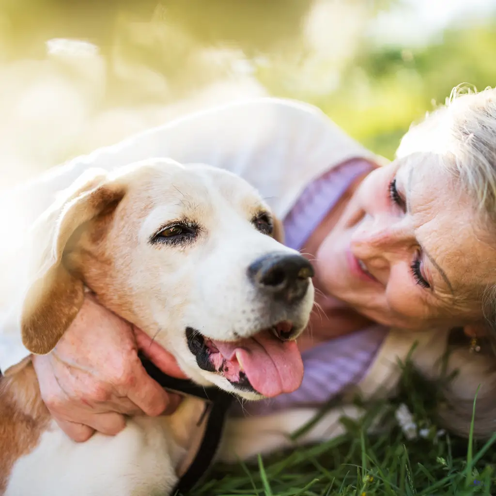 A lady playing with her emotional support dog in the park.